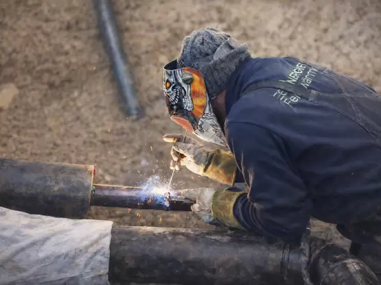 Nahaufnahme eines Schweisser beim Arbeiten im Graben