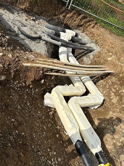 Fernwärmerohr mit vorbereiteten Hausanschlüssen im Graben.