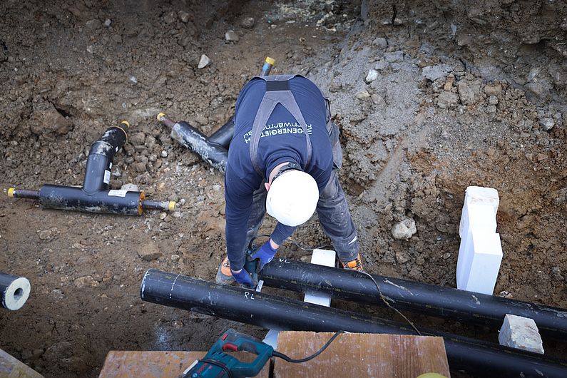 Mitarbeiter am Verlegen von Fernwärmerohren im Graben 