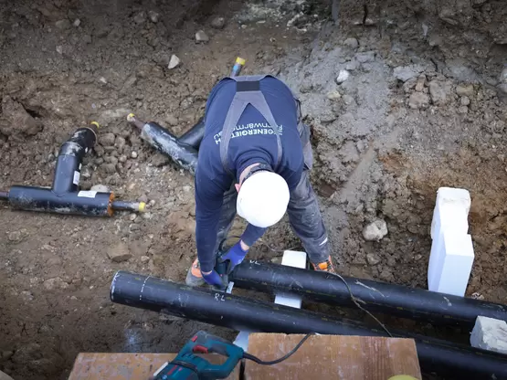 Mitarbeiter am Verlegen von Fernwärmerohren im Graben 