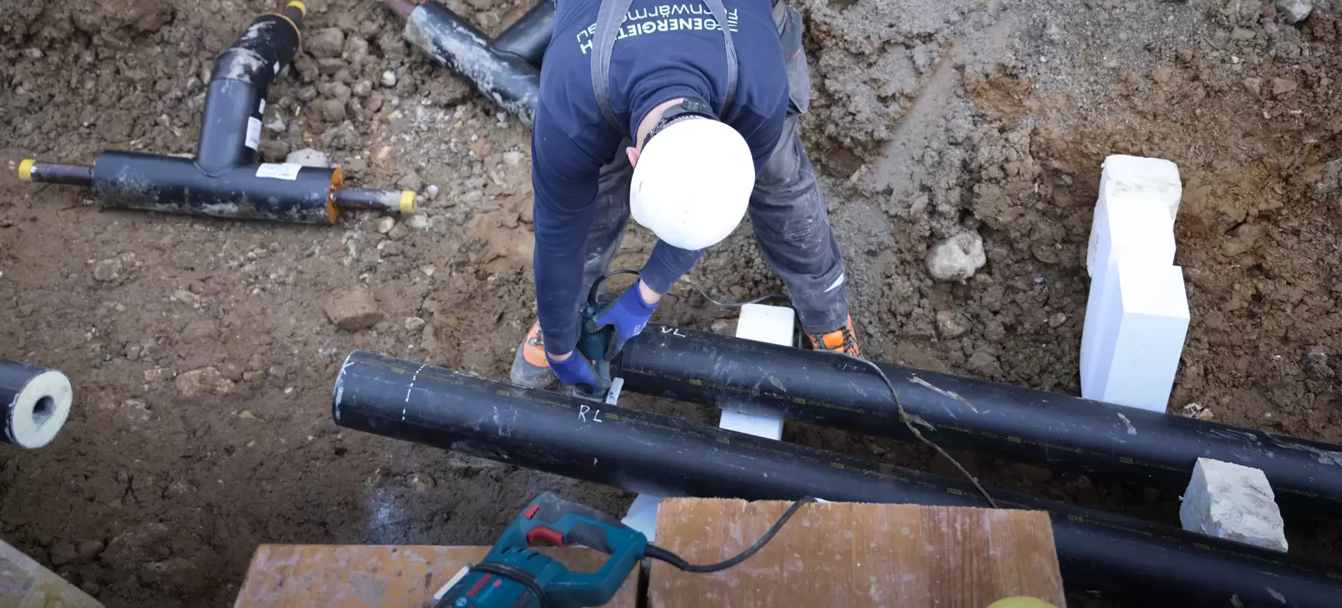 Mitarbeiter am Verlegen von Fernwärmerohren im Graben 