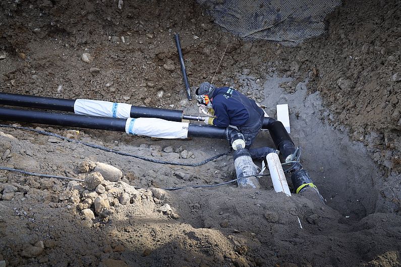 Schweisser sitzt auf Rohr im Graben
