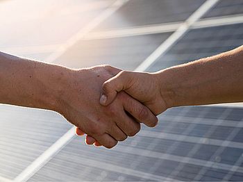 Händeschütteln vor Photovoltaikanlage