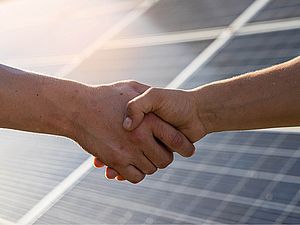 Händeschütteln vor Photovoltaikanlage