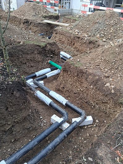 Fernwärmerohr im Graben mit vorbereiteten Hausanschlüssen.